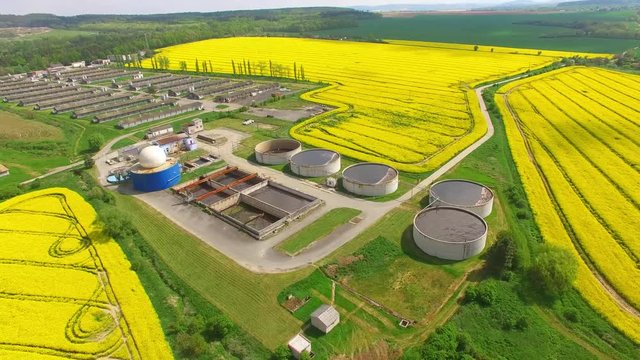 Camera flight over biogas plant from pig farm in rapeseed fields. Renewable energy from biomass. Modern agriculture in Czech Republic and European Union. 