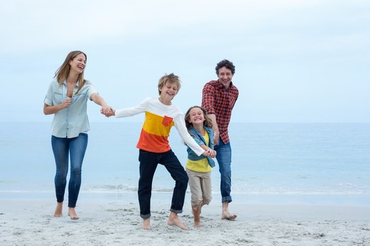 Cheerful family holding hands while running at sea shore