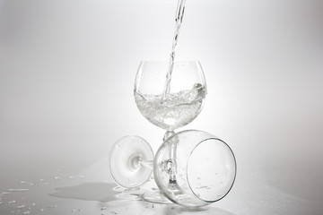 Water pouring from bottle into the glass, isolated on white