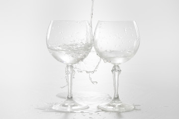 Water pouring from bottle into the glass, isolated on white
