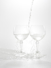 Water pouring from bottle into the glass, isolated on white