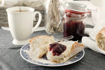 Fresh baguette with strawberry marmalade and a cup of tea for breakfast