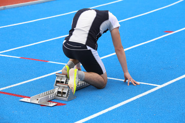 muscular young athlete in the starting blocks of a athletic trac