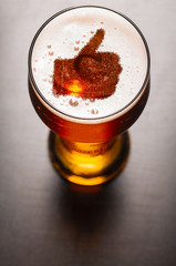 loving beer, thumb symbol on foam in glass on black table, view from above