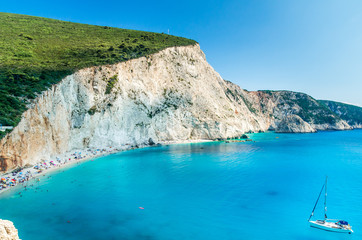 Porto Katsiki beach in Lefkada island, Greece. Beautiful view over the beach. The water is turquoise and there are tourists on the beach and a boat on the sea.