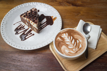 Sweet chocolate ship cake with syrup and hot art of coffee on the dish