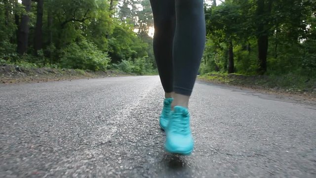 Runner woman running at road in forest. Feet close up. Shot with steadicam