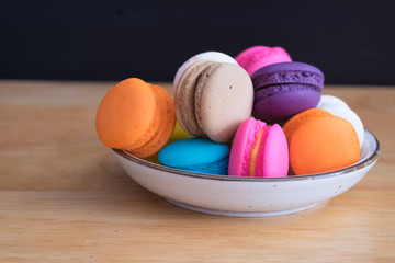 colorful macaroon in white ceramic plate with all flavors on wooden table/colorful macaroon in ceramic plate

