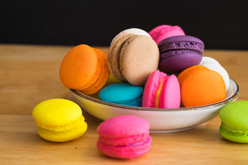 colorful macaroon in white ceramic plate with all flavors on wooden table/colorful macaroon in ceramic plate
