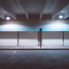 No parking sign in front of a storage units with a blue awning inside a parking garage, at night.