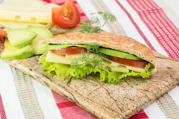Pita pocket sandwich with cheese, avocado, tomato and lettuce.