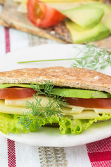 Pita pocket sandwich with cheese, avocado, tomato and lettuce.
