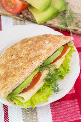 Pita pocket sandwich with cheese, avocado, tomato and lettuce.