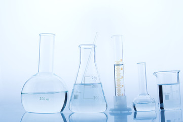 Different laboratory glassware with water and empty with reflection on white background