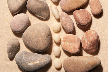 Pink and grey toned sea stones separated by white on sand