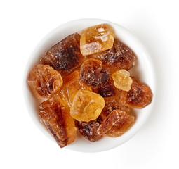 Bowl of caramel sugar crystals isolated on white, from above