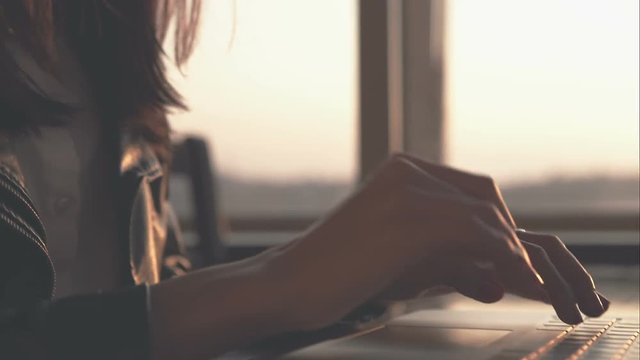 Woman typing on a laptop keyboard in a warm sunny day outdoors. Sunset. RAW video record.