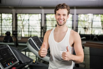 Happy man showing his thumbs up at gym