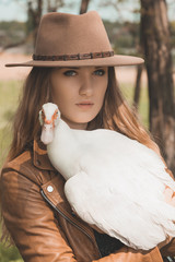 Girl in brown hat keeps white duck on her hands. Portrait of a w © kisses_illusion