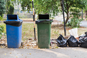 Old large wheel bins and pile of full garbage bags
