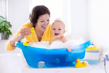 Young mother bathing baby boy