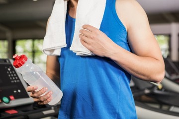 Man on treadmill holding water bottle at gym