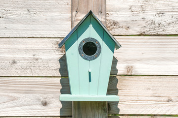 Blue birdhouse on a wooden fence