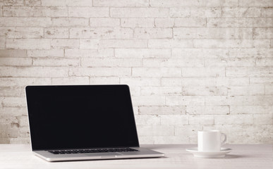 Business laptop with white brick wall