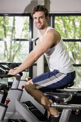 Fototapeta na wymiar Man working out on exercise bike at spinning class
