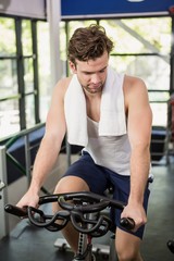 Fototapeta na wymiar Man working out on exercise bike at spinning class