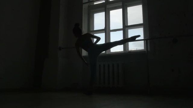 Silhouette of a Ballet Dancer Exercising at The Barre By The Window