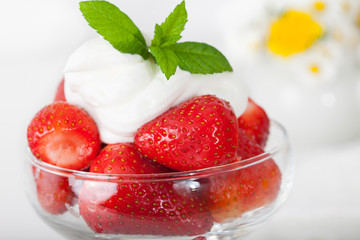 Fresh strawberries in the bowl with whipping cream and mint leaves