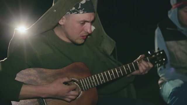 One man playing the guitar at night for the soulmates