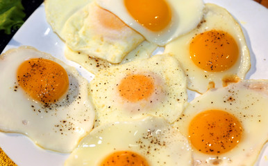 many fried eggs with red yolk  with a sprinkling of pepper over