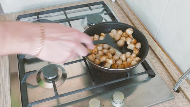  young man fries the dumplings  in a  pan, side view 