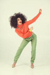 Young woman wearing retro clothes striking a pose in studio. Disco diva