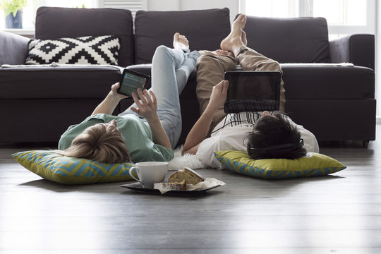 Caucasian couple using digital tablets on floor
