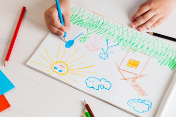 Child draws a pencil drawing of the house and his family.