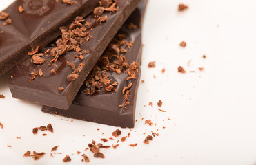Pieces from a chocolate bar and chocolate crumbs on a white back