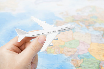 Studio shot of toy plane in hand with world map on background - focus on the plane
