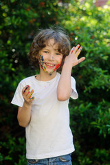 Cute boy, his face and hands in the paint