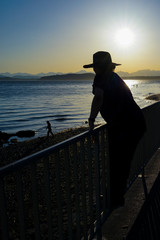 Fototapeta premium Female Wearing Sun Hat Standing By Railing Silhouette
