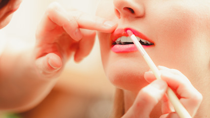 Naklejka premium Make up artist applying lipstick with brush.