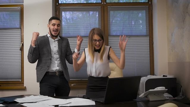 The young girl and the guy in the office. Successful completion of the transaction through the Internet, elation and emotion. Young business people celebrate their success.