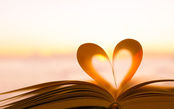 Heart shape from a book page against a beautiful sunrise.
