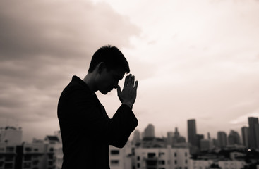 Man praying in a city setting. 