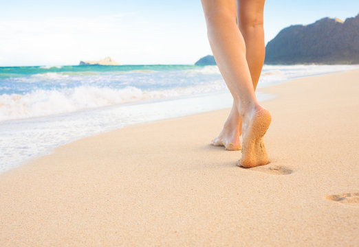 Woman walking on white sand beach in Hawaii. 