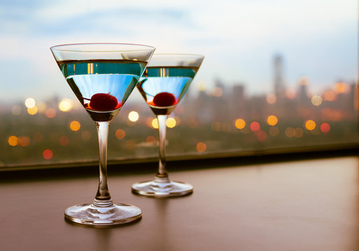Cocktail glasses with city lights in the background.  

