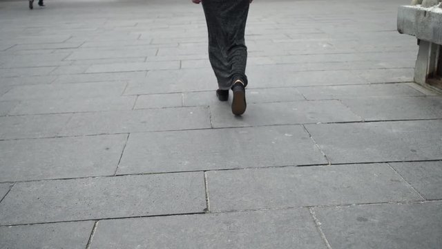 Female wearing in maxi dress long grey.  Model moves on pavement. Holding smartphone in her hand