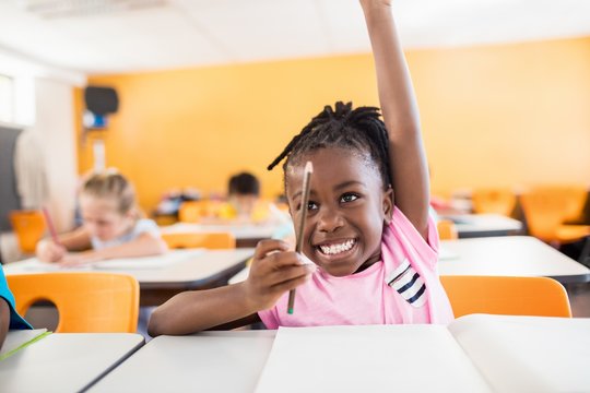 elementary students raising hands in class